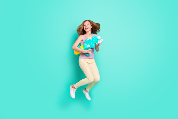 全身照，女孩夏天拿着水枪跳起来，背景是充满活力的蓝绿色图片下载