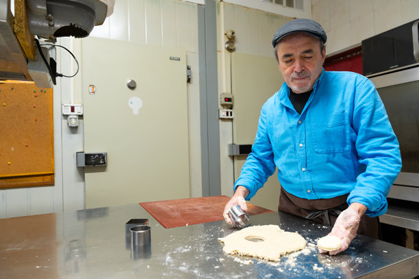 年长的面包师正在使用饼干模具准备面团图片下载