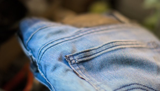 蓝色牛仔裤的特写微距摄影，展示了褪色、磨损的旧牛仔布料口袋的细节，风格复古，适合服装时尚图片下载
