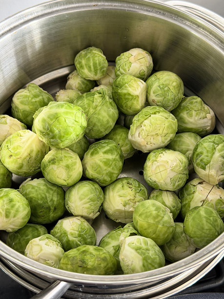 全画幅圣诞晚餐食材图片，一堆新鲜剥皮的生抱子甘蓝放在金属蒸锅里，准备蒸制，俯视角度图片下载