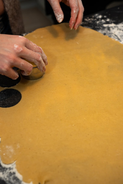 一位女性在家庭圣诞节假期期间，在厨房餐桌上使用饼干模具制作节日饼干。图片下载