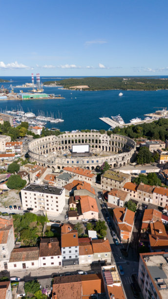 阳光明媚的海滨城市，古罗马圆形剧场与港口的全景航拍照片图片下载
