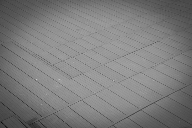 一张充满氛围的黑白木质栈道照片，高视角和黑暗的角落吸引着目光沿着木板强烈的几何线条延伸。图片下载