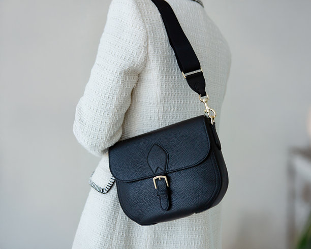 模特手中展示的黑色女士小手袋。现代时尚手袋照片。日常生活中的时尚配饰图片下载