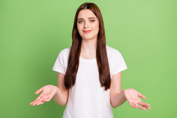 照片：一个不开心、怀疑、茫然的年轻女子耸着肩膀，表示不知道，孤立在绿色的背景上图片下载