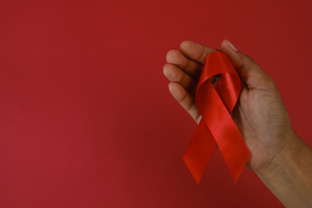 手持红色丝带，这是世界艾滋病日象征团结、意识和支持艾滋病患者的有力标志。这张图片代表了全球社区的同情心和共情。图片下载