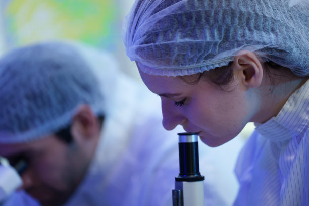 国际男女技术人员身穿无菌服在半导体制造工厂工作，并使用显微镜（照片）图片下载