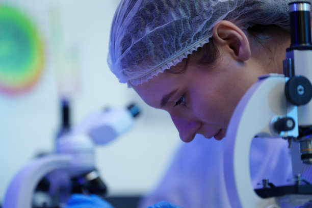 国际男女技术人员身着无菌服，在半导体制造工厂使用显微镜工作（照片）图片下载