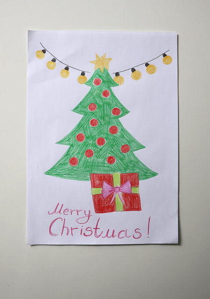 儿童画特写照片。圣诞树装饰有花环、星星、礼物，并写有“圣诞快乐！”的祝福语。图片下载