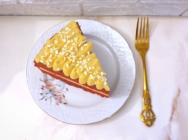 精致花卉瓷盘上盛着一块优雅的红丝绒蛋糕，旁边放着一把复古风格的金叉图片下载