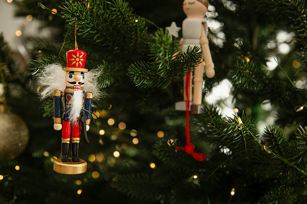 装饰在圣诞树上的传统木制胡桃夹子圣诞装饰品，配有温暖的灯光和金色饰球。节日气氛，营造舒适的冬日心情。图片下载