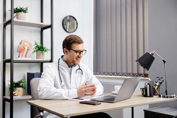 医生在诊所办公室的桌子前，通过笔记本电脑屏幕与在线患者交谈，提供远程医疗家庭健康治疗咨询。远程医疗远程医疗预约。图片下载