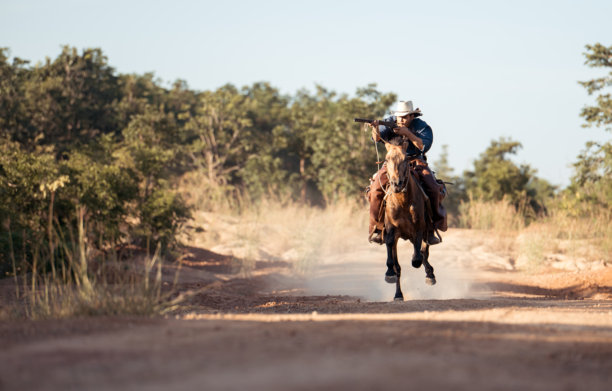 一匹扬起前蹄的马上的牛仔，手持左轮手枪，画面经典而富有戏剧性图片下载