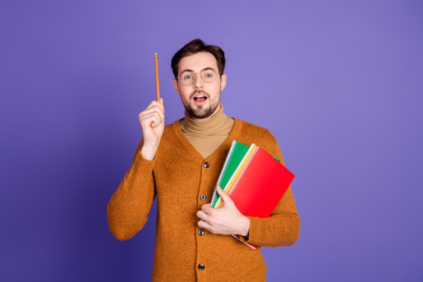 戴眼镜的年轻英俊男学生手持笔记本和铅笔，带着微笑，背景为紫罗兰色，适合广告和时尚生活方式图片图片下载
