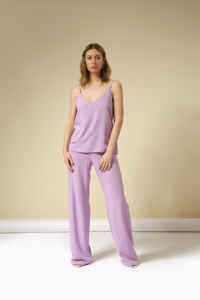 年轻女模特在影棚拍摄的系列照片，身着亚麻浅紫色套装，包括无袖上衣和舒适长裤。休闲时尚的装扮，春夏时尚潮流。图片下载