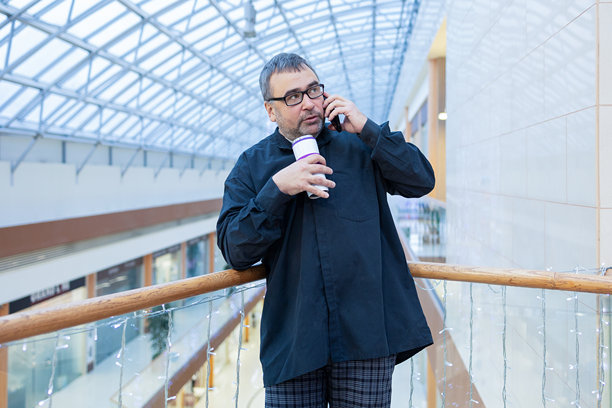 男人在现代商场里边喝咖啡边打电话图片下载