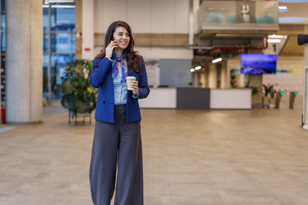 女商人走在办公楼大堂，边走边打电话图片下载
