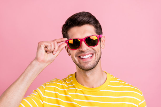 照片：快乐年轻积极的男人戴着太阳镜，心情很好，周末，背景色为粉色图片下载