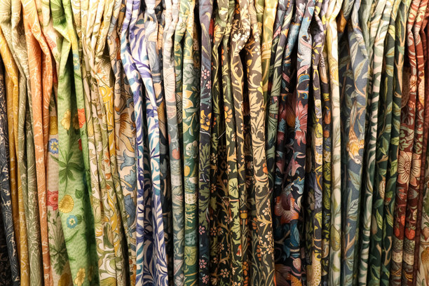 悬挂在色彩缤纷的展示中的复古纺织品上的多样化花卉和植物图案图片下载