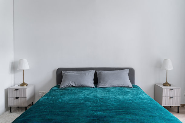宽敞明亮的卧室，配有双人床。床上铺着绿色床罩和枕头。不同光线下的卧室照片。图片下载