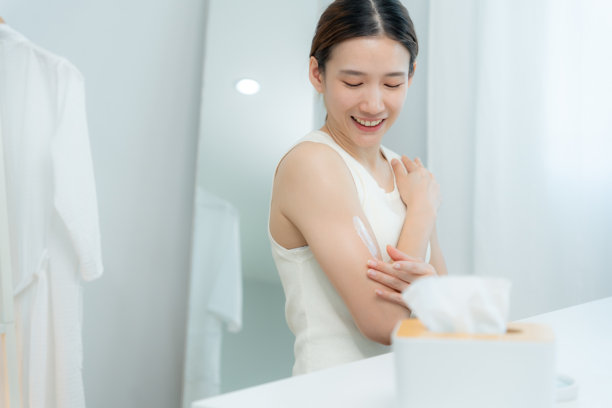 美丽的亚洲女性微笑着使用护肤霜以获得良好肌肤。健康的女性涂抹身体乳。护肤霜广告，抗皱，婴儿肌，美白，保湿，收紧毛孔精华图片下载