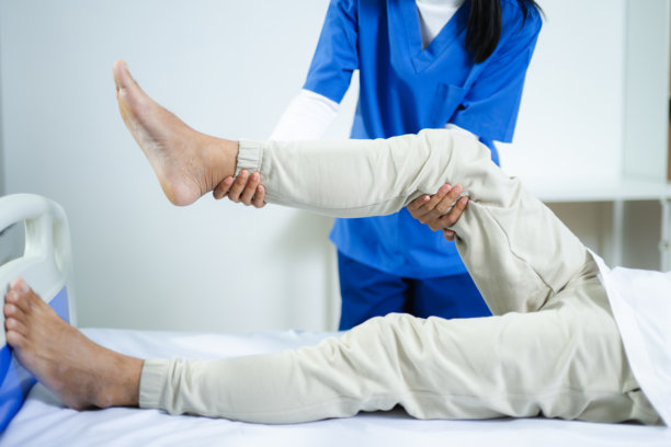 理疗师帮助一位老年男子伸展腿部。非常适合物理治疗、伤病康复、老年护理、活动能力支持和医疗保健素材图库。图片下载