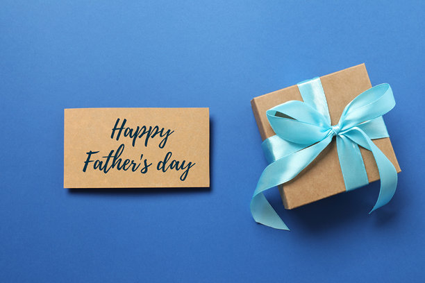 父亲节快乐。蓝色背景上丝带蝴蝶结礼品盒的俯视照片图片下载