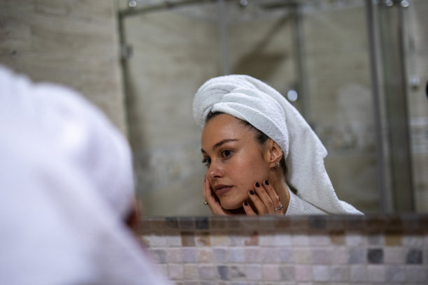 女性在浴室镜子前使用护肤品。图库图片图片下载