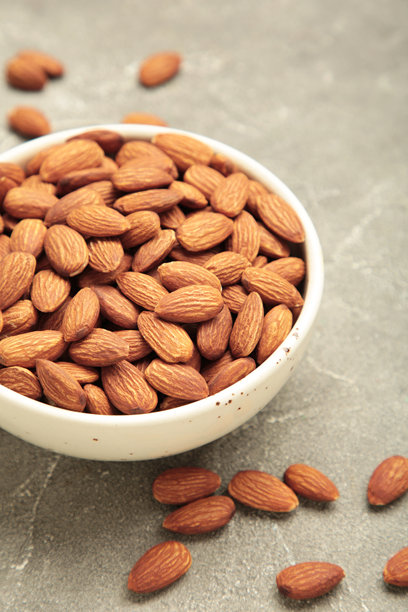 灰色背景上的碗装杏仁。完整干果。竖直照片图片下载