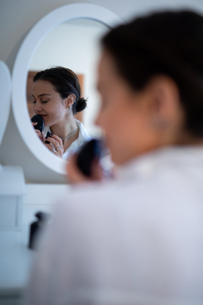 一位女性正在享受美容日常，涂抹化妆粉。图库图片图片下载