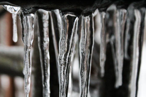 金属表面悬挂着锋利、清晰的冰柱的特写照片。图片下载