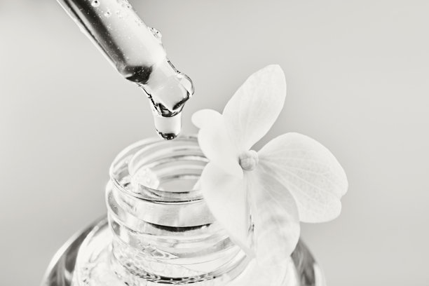 移液管将透明液体精华滴入带有花朵的瓶中，单色。年度色彩概念图片下载