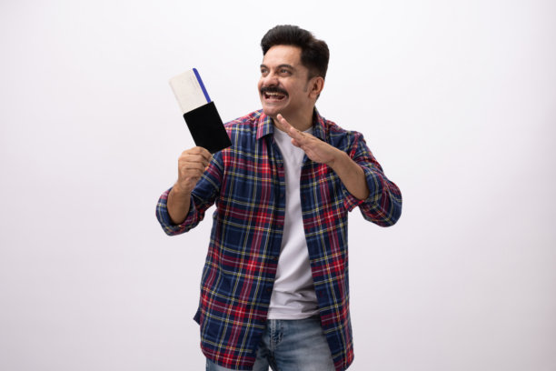 英俊、兴奋的中年男性，手持护照，身穿格子衬衫，在白色背景下拍摄的照片素材图片下载