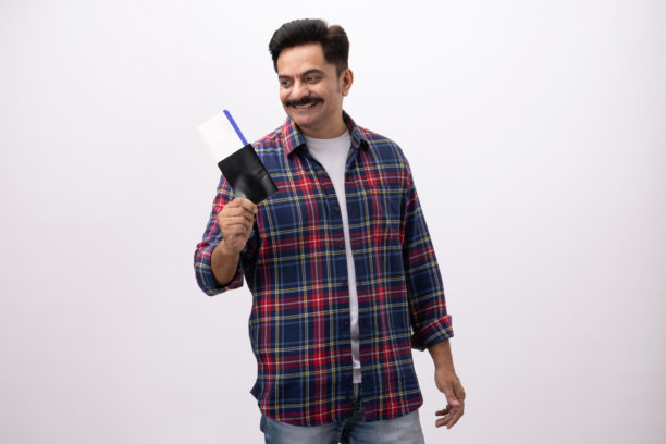 英俊兴奋的中年男子，身穿格子衬衫，手持护照，在白色背景下孤立拍摄的素材照片图片下载