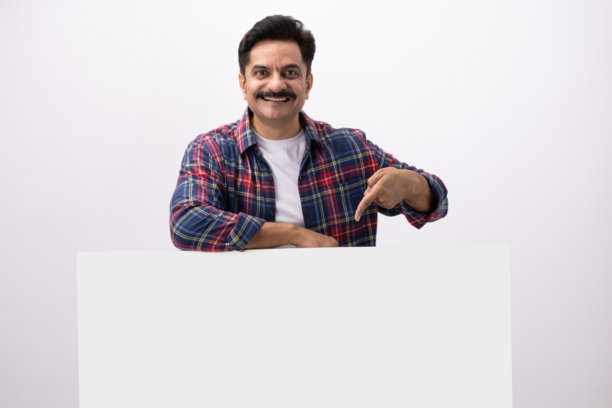 英俊的成年男性穿着格子衬衫，躲在空白的白墙后面，素材照片图片下载