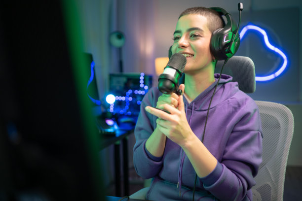 内容创作者或主播对着麦克风唱歌，同时与电脑屏幕互动图片下载