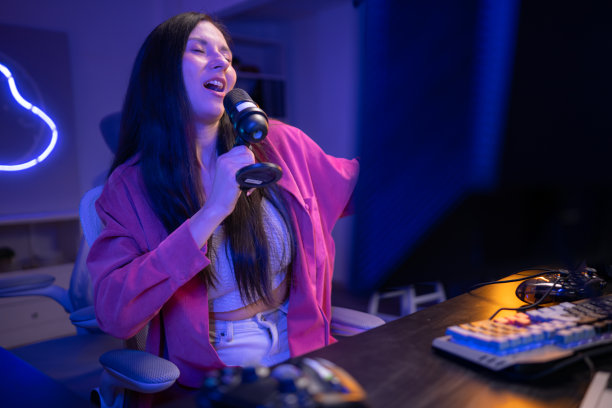 内容创作者或主播对着麦克风唱歌，同时与电脑屏幕互动图片下载