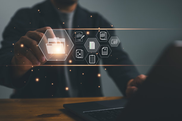 一位商务专业人士的特写照片，他正在使用笔记本电脑数字化管理文件和文档，文件夹图标漂浮在空中。图片下载