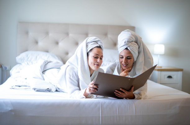 穿着浴袍的朋友们在挑选酒店客房送餐服务菜单的素材图图片下载