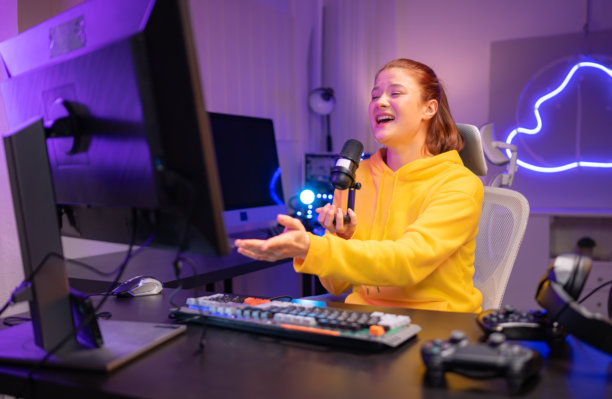 内容创作者或主播对着麦克风唱歌，同时与电脑屏幕互动图片下载