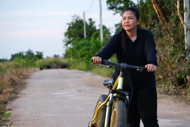 一位女士骑山地车在土路上休息，神情严肃地向前望去。图片下载