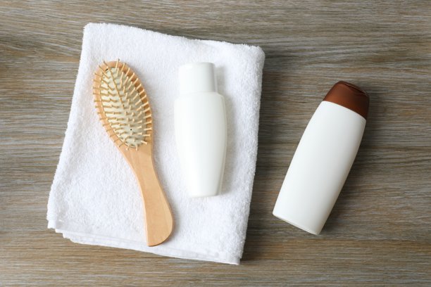 洗发水、毛巾和梳子放在木质背景上，俯视视角图片下载
