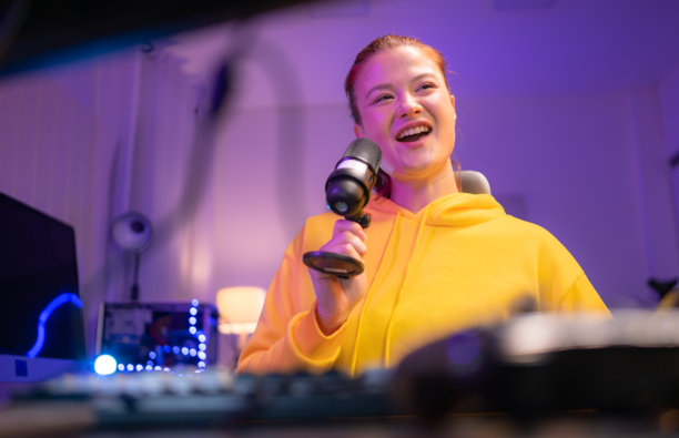 一位内容创作者或主播对着麦克风唱歌，同时与电脑屏幕互动图片下载