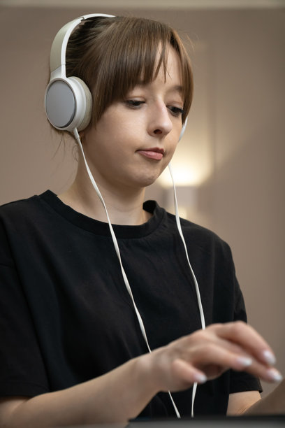 戴着耳机在家工作的专注女孩，在现代家庭办公室的办公桌前用笔记本电脑打字，专注于在线任务。竖屏照片图片下载