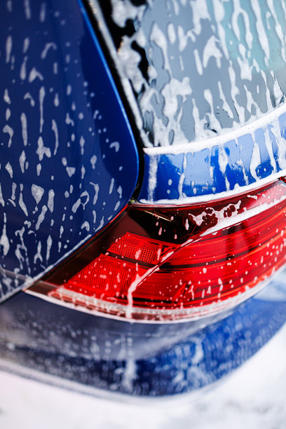 特写照片。汽车零件覆盖着厚厚的泡沫。用于清洗肮脏车辆的化学品。图片下载