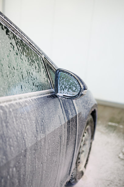 特写照片。带有厚泡沫的汽车零件。用于清洗脏污车辆的化学品。图片下载