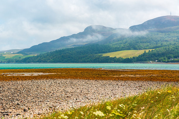 隐藏的苏格兰。NC500路线。拥有绿松石般海水、岩石海滩和薄雾笼罩的翠绿山丘的海岸山地景观图片下载