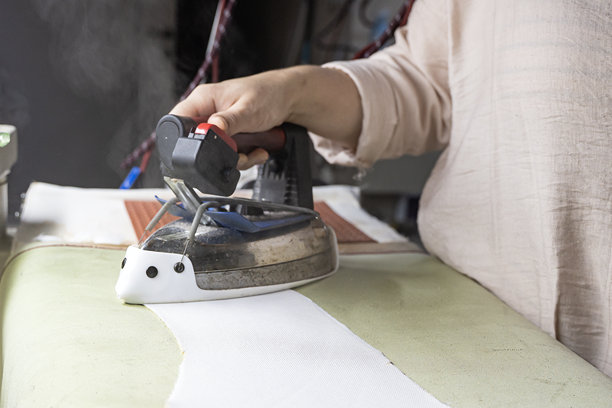 一位女士在婚纱店里拿着专业的熨斗。素材照片图片下载