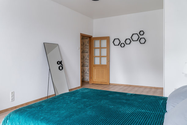 宽敞明亮的卧室，配有双人床。床上有绿色的床罩和枕头。不同光线下卧室的照片。房间里有一个大大的白色衣柜。图片下载