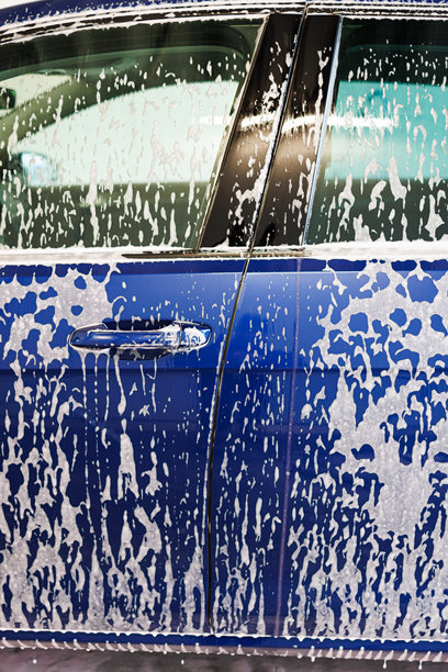 特写照片。带有厚泡沫的汽车零件。用于清洗脏污车辆的化学品。图片下载